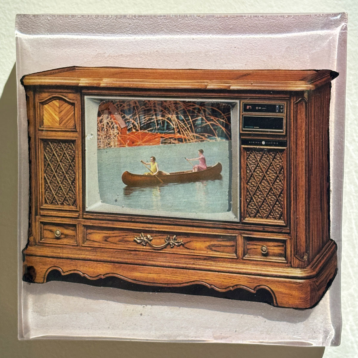 Wooden television set with a scene of two people in a canoe on the screen.