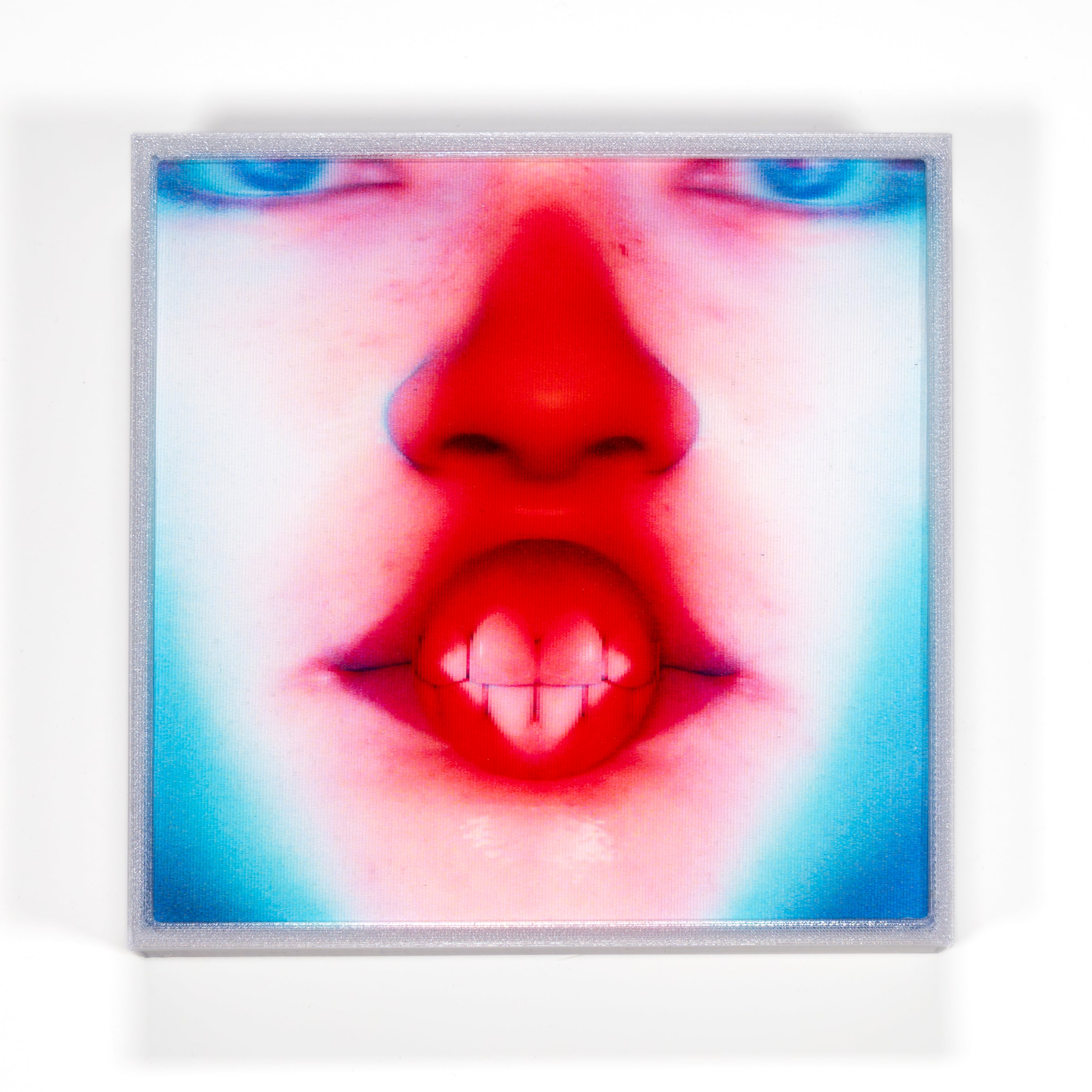 Close-up of a person's face with a red nose and blue eyes, framed by a white border.