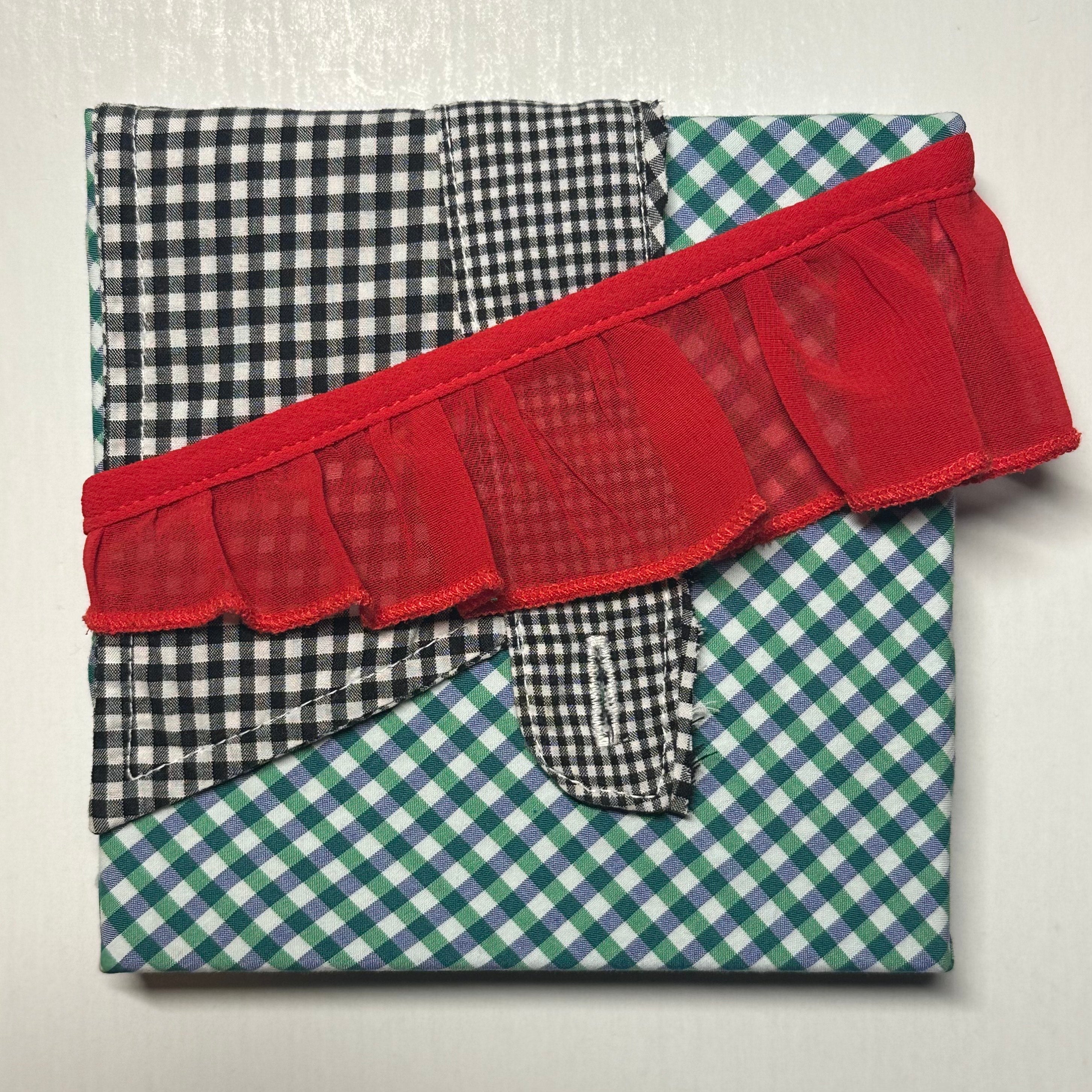Folded fabric with red ruffled trim on a white background