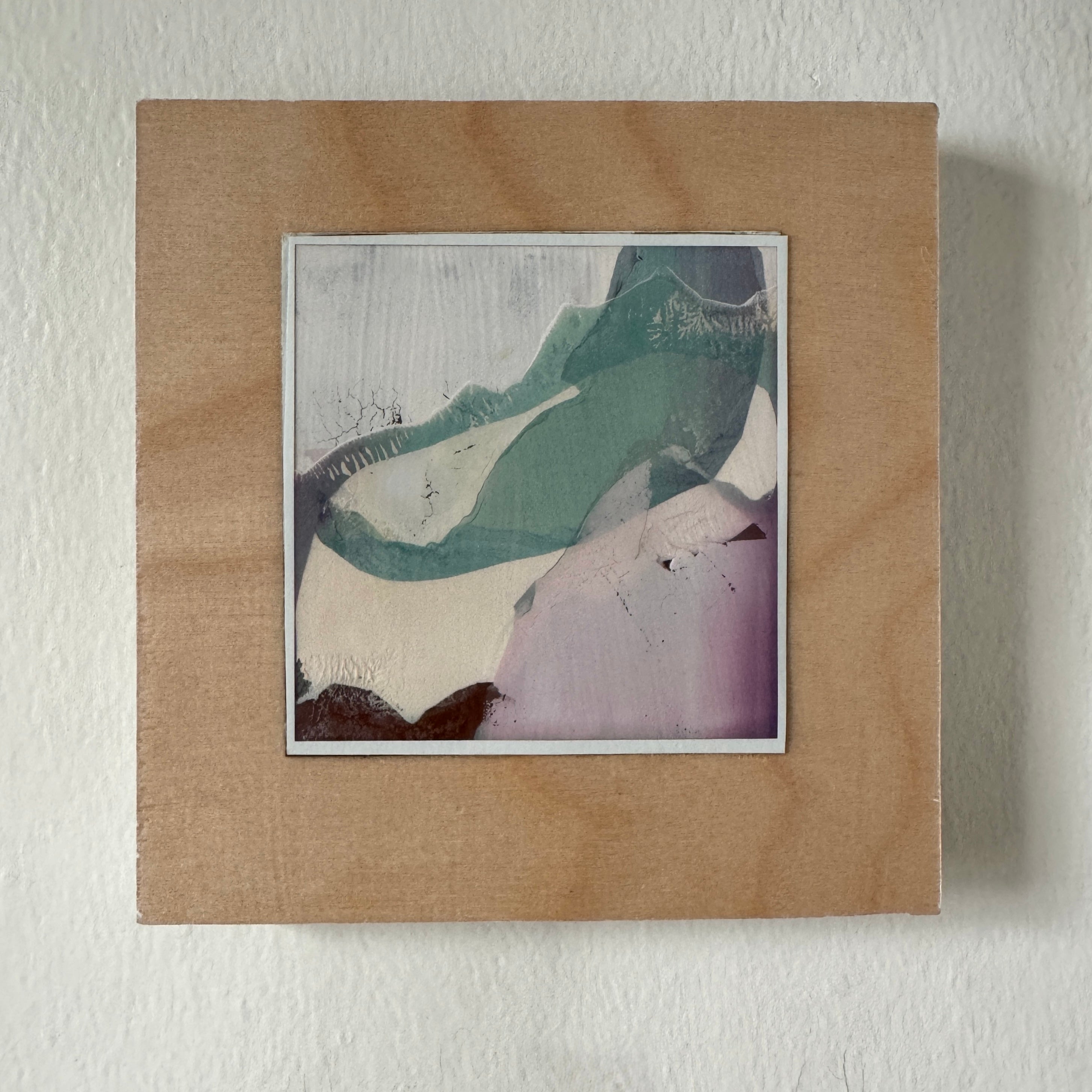Framed abstract artwork with a textured brown frame on a white wall