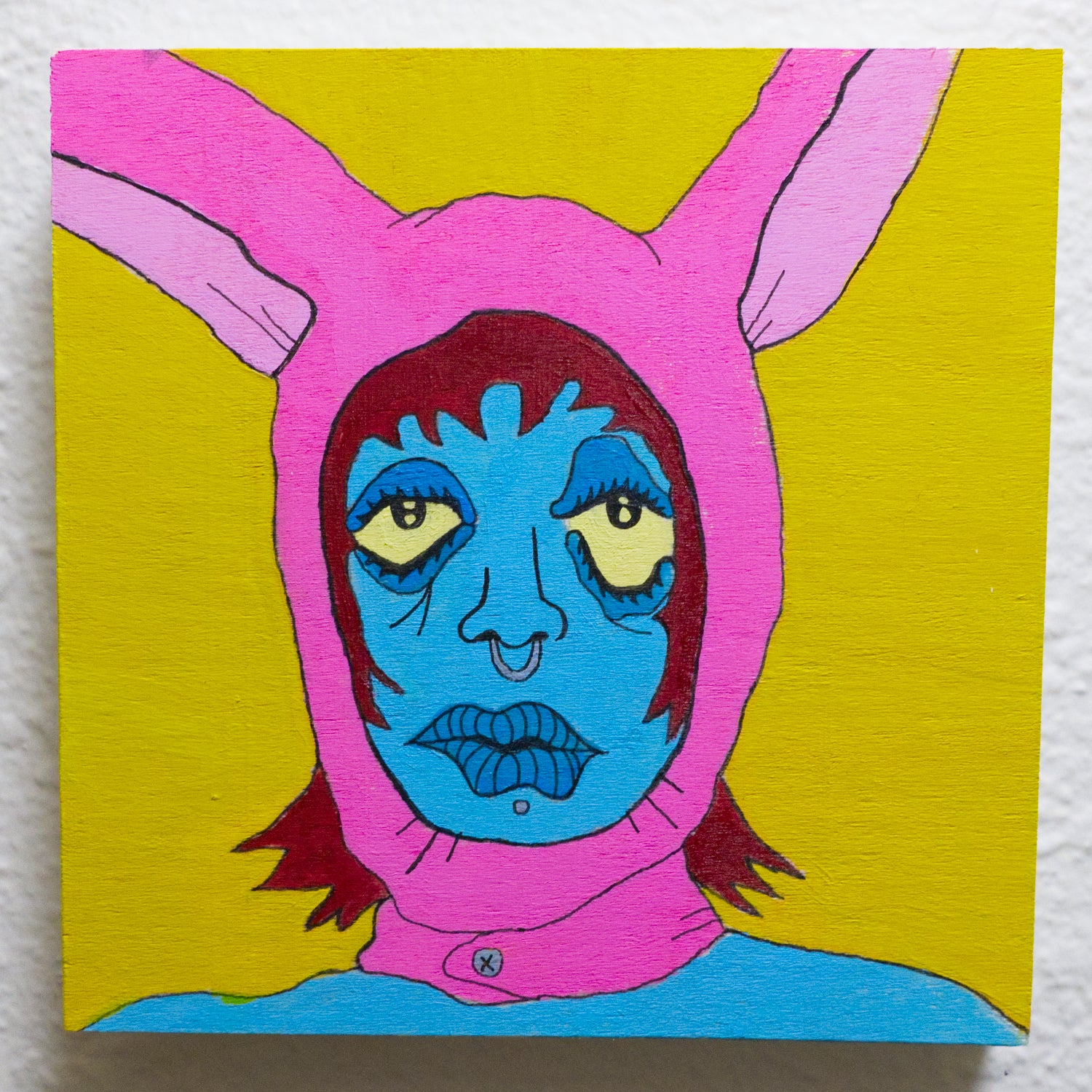 Surreal painting of a character with pink bunny ears and blue face on a yellow background