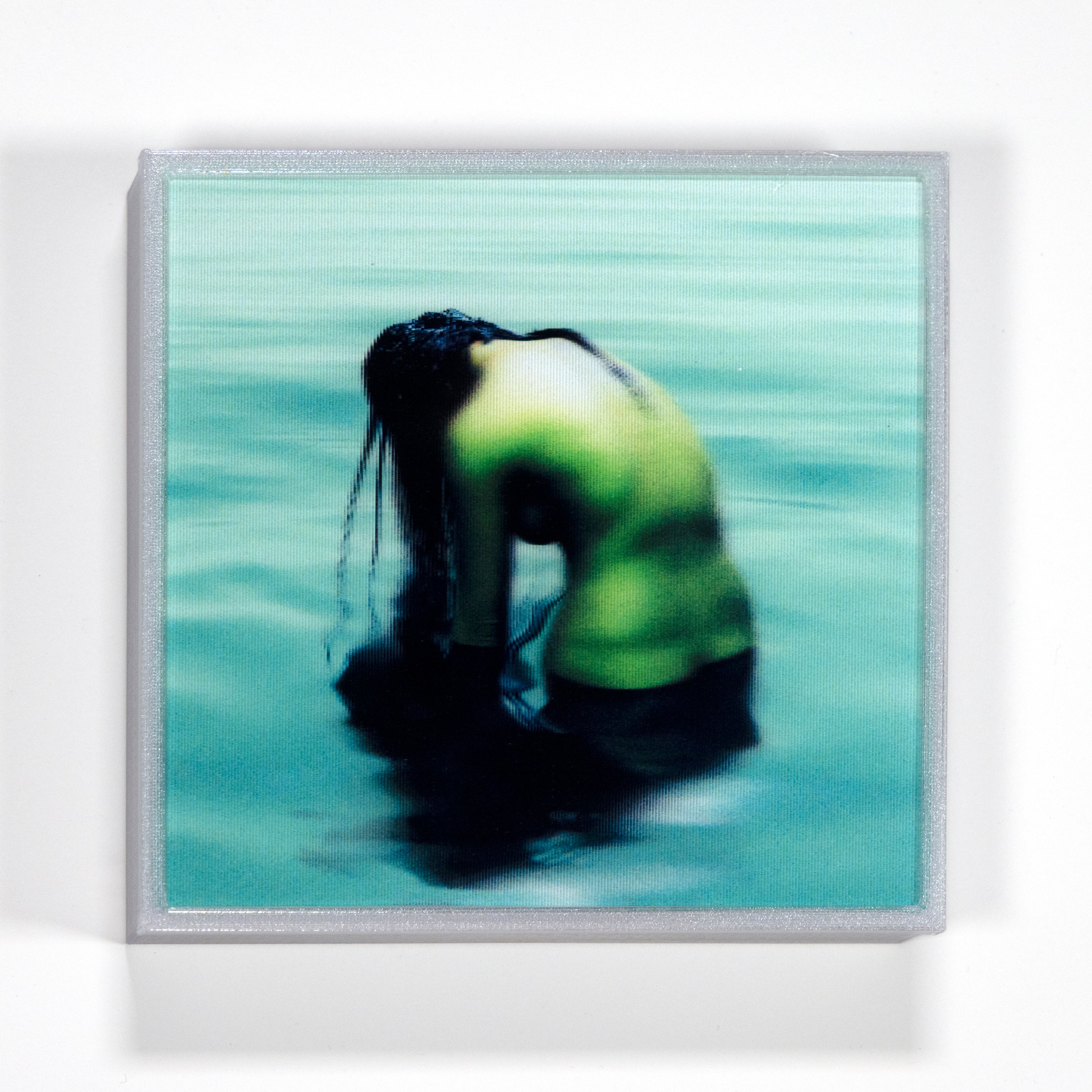 Person in a green shirt sitting in water with a blurred background