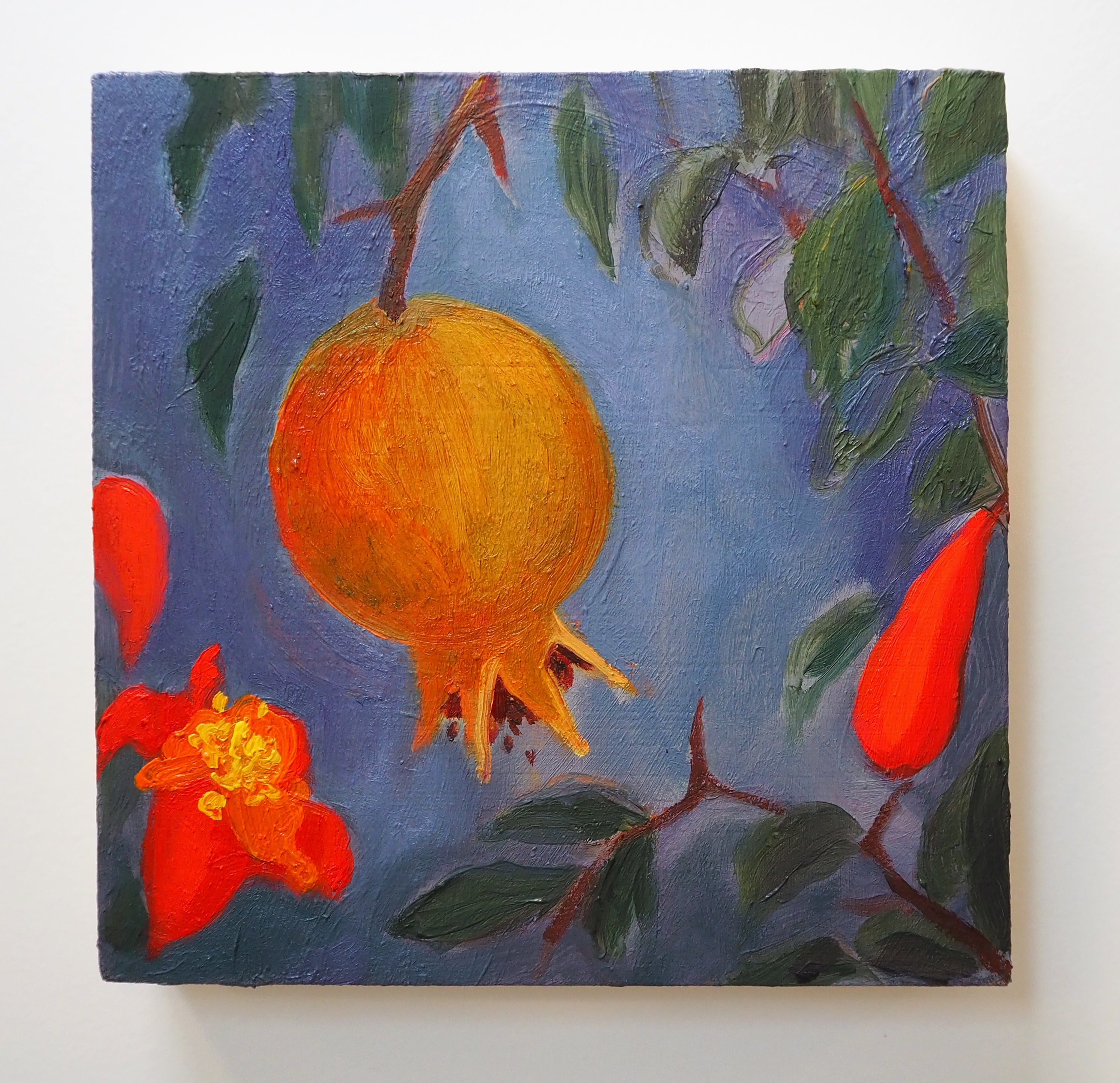 Painting of a pomegranate fruit with leaves and flowers on a blue background