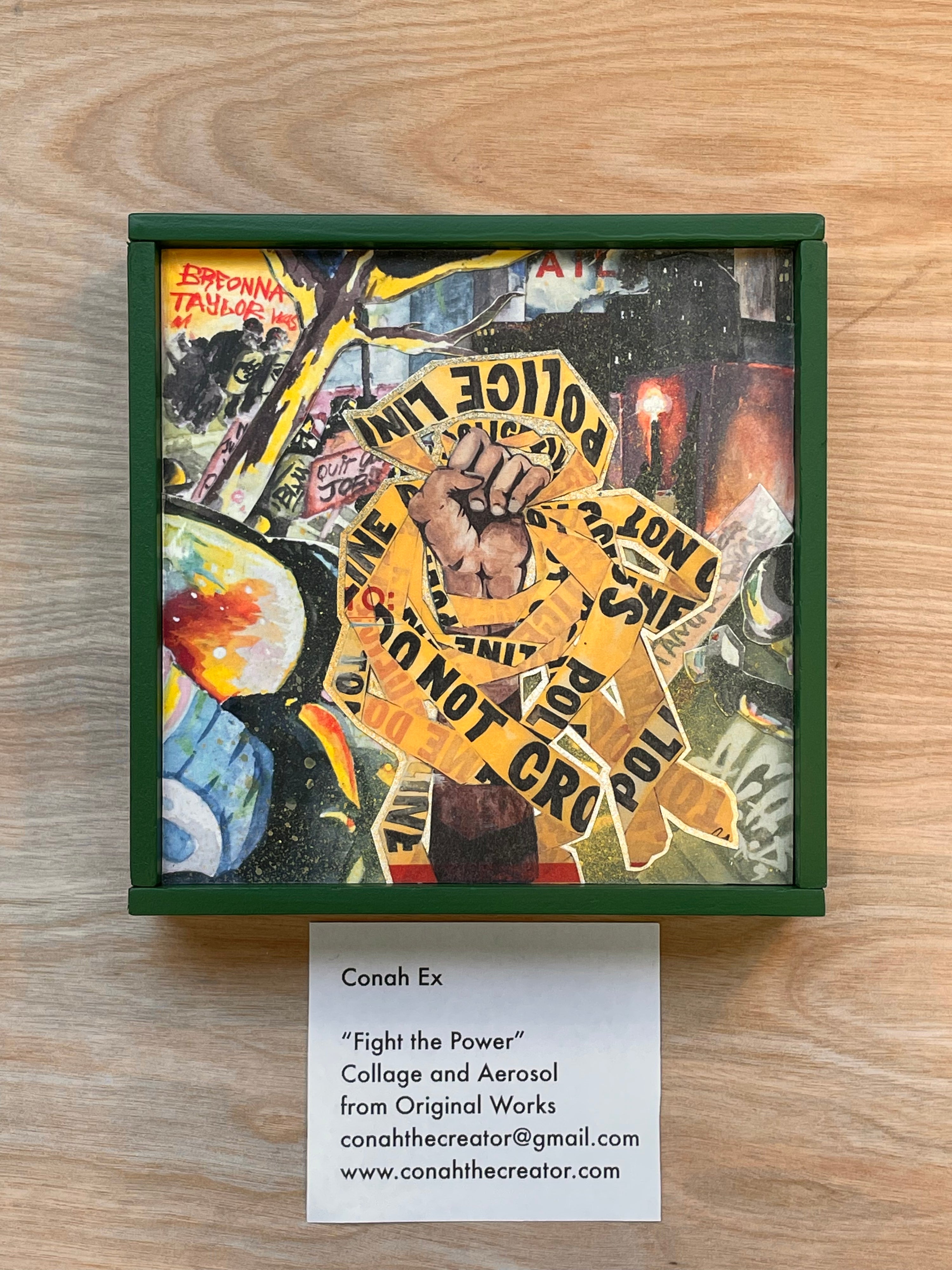 Collage artwork with text and symbols on a wooden surface, featuring a card with artist information.