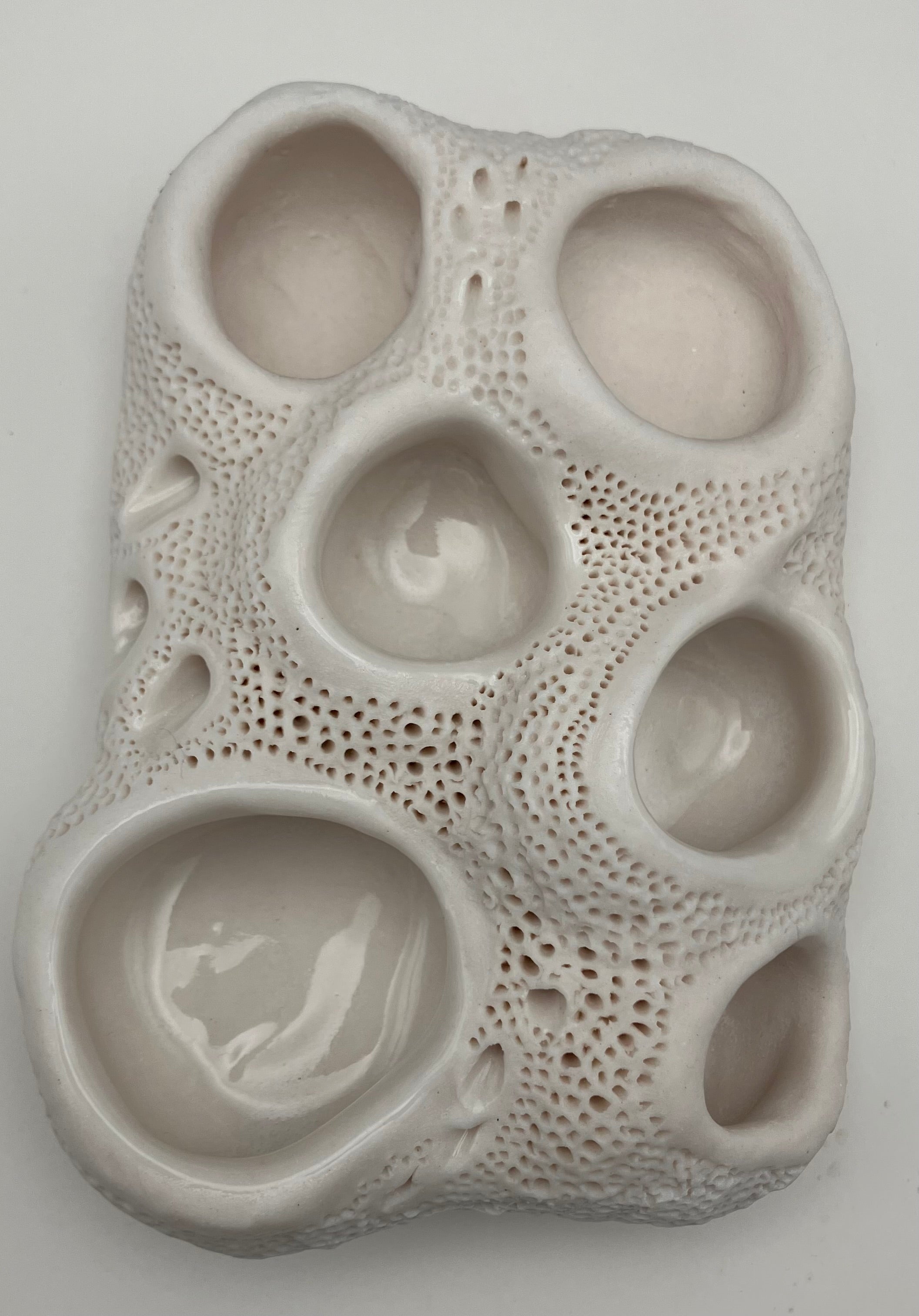 Ceramic art piece with textured surface and embedded design on a gray background