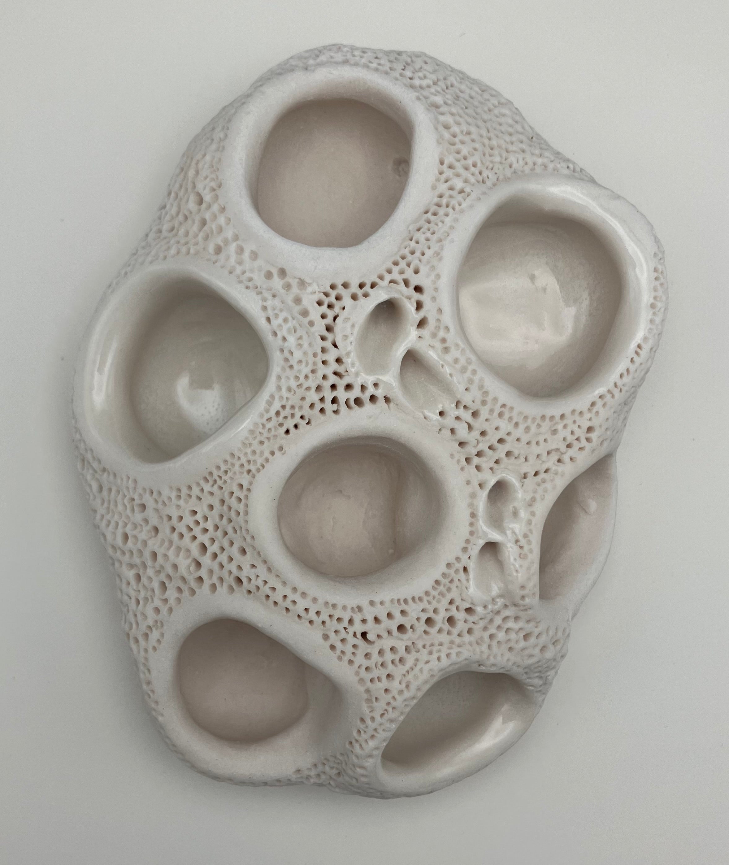 Textured ceramic wall art piece on a plain background