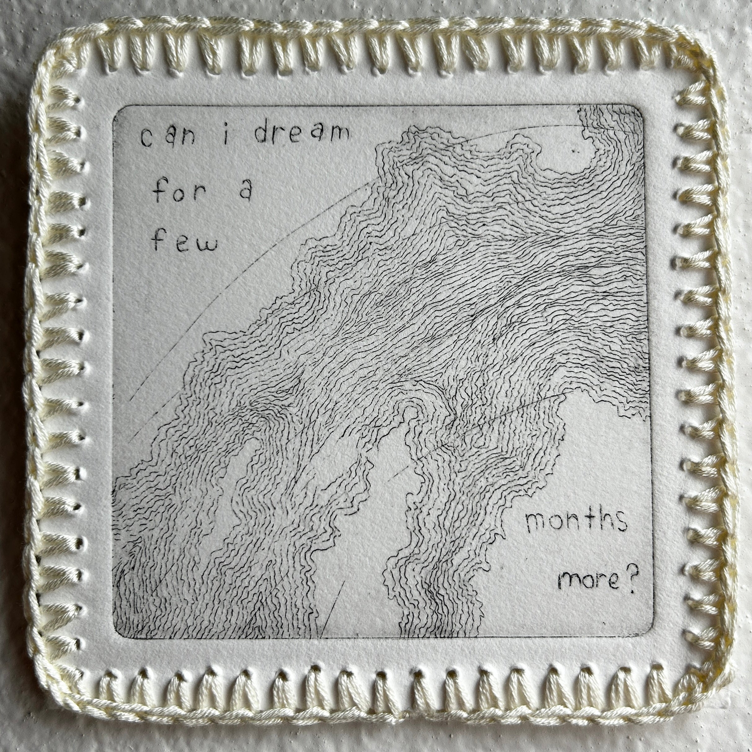 Decorative square object with engraved text and wavy pattern on a textured surface