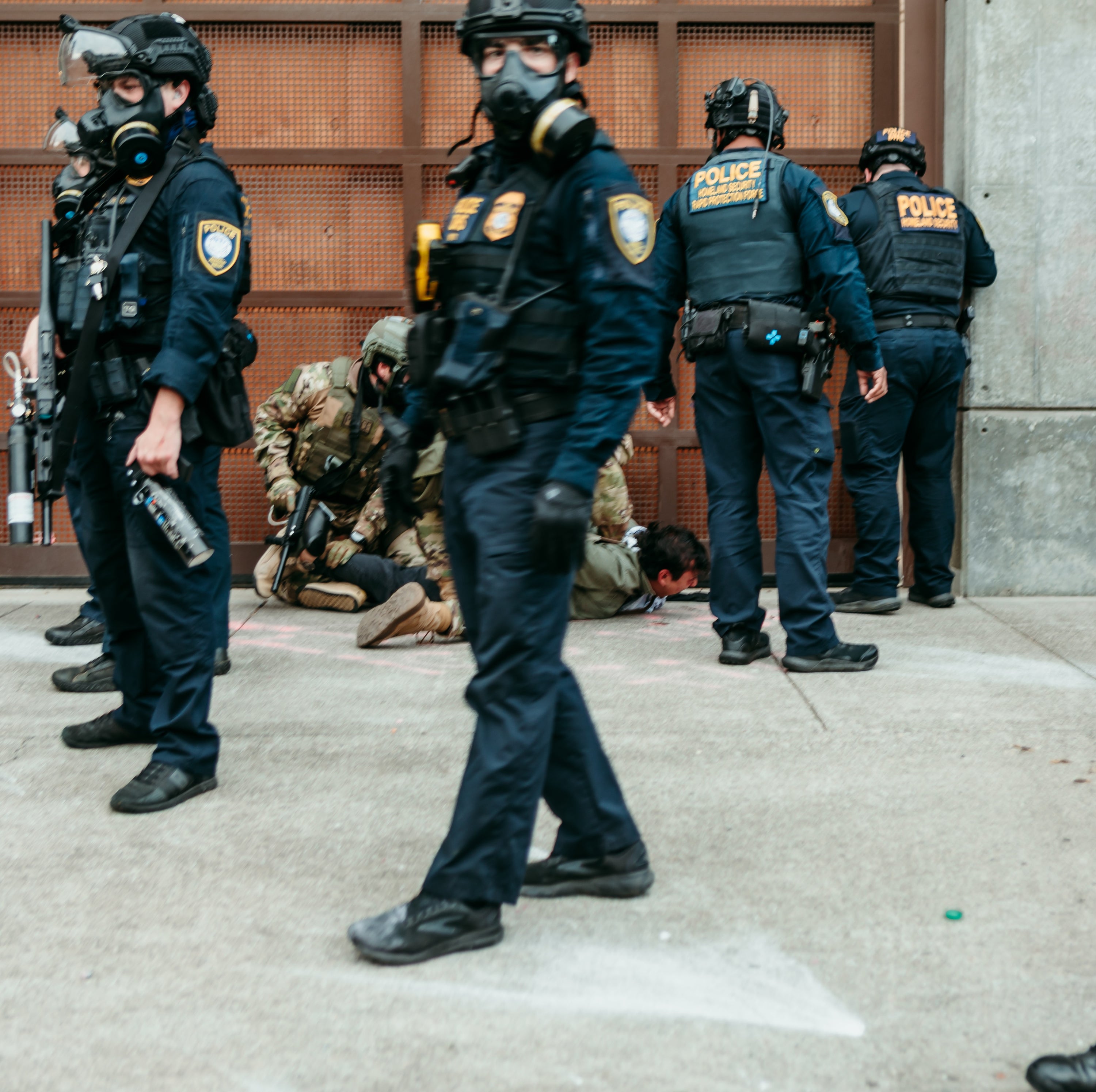 Police officers in tactical gear with gas masks on a city street.