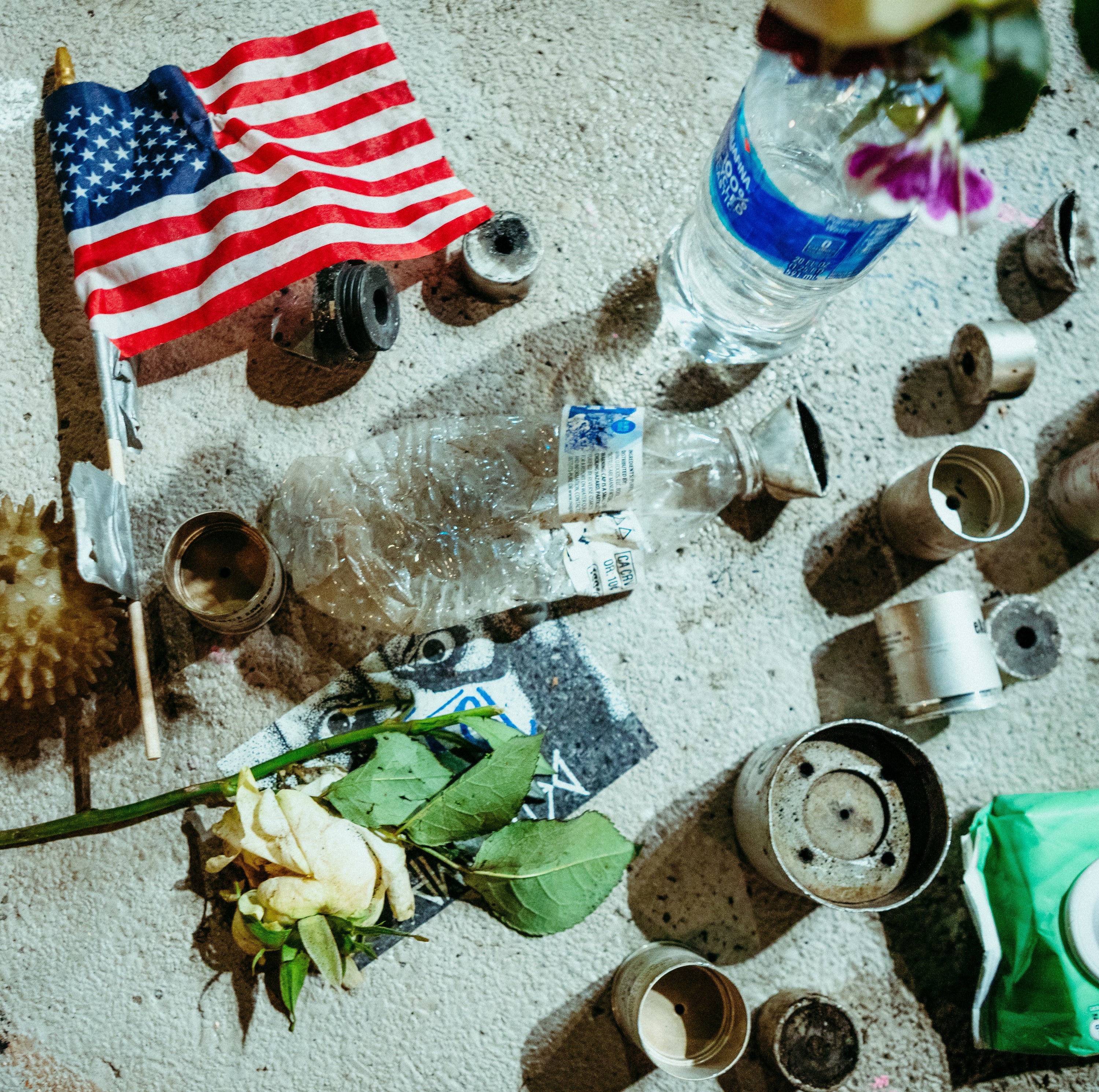 Scattered items including a U.S. flag, bottles, and flowers on a textured surface.