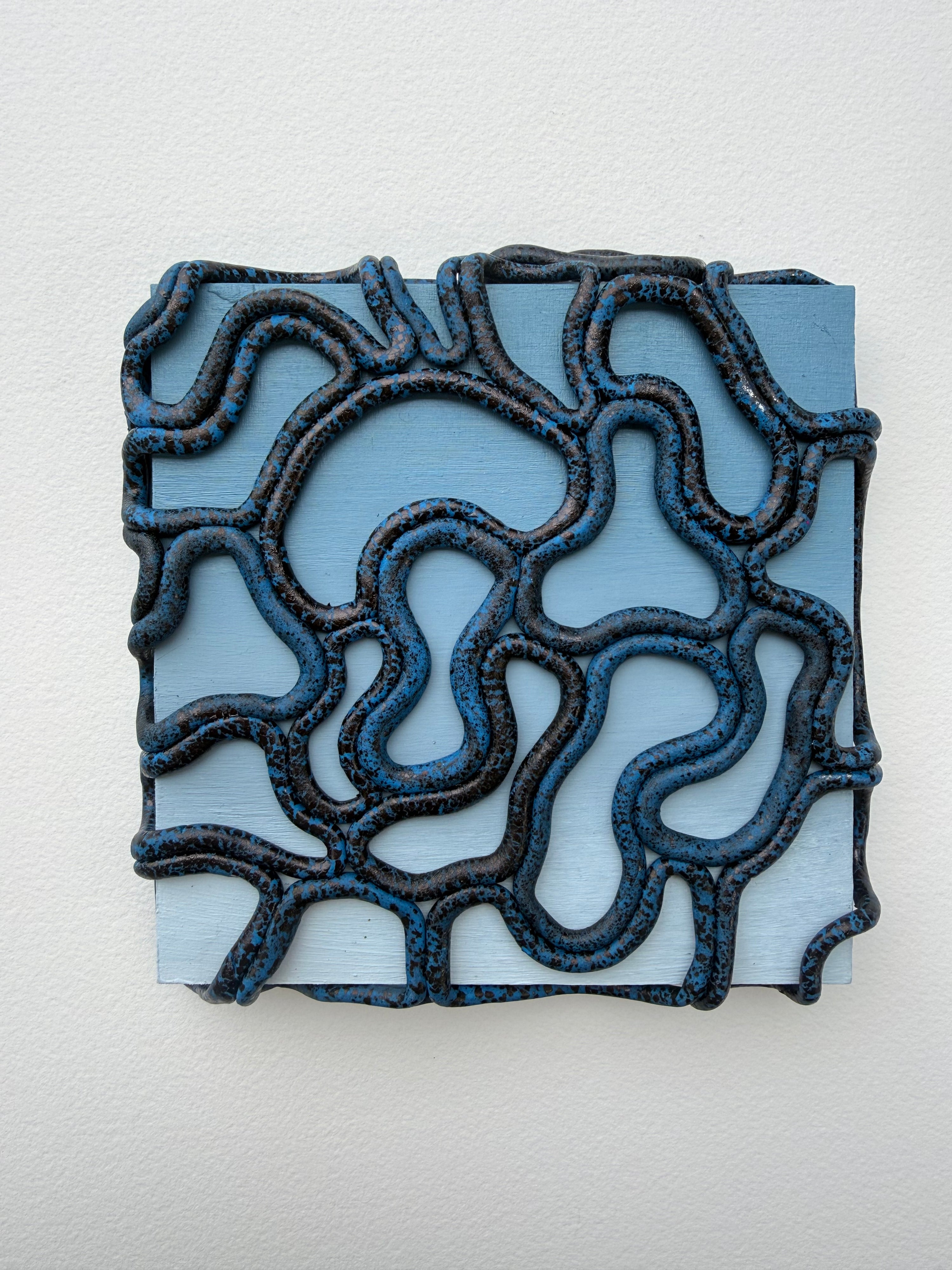 Decorative wall tile with intricate black pattern on a light gray background