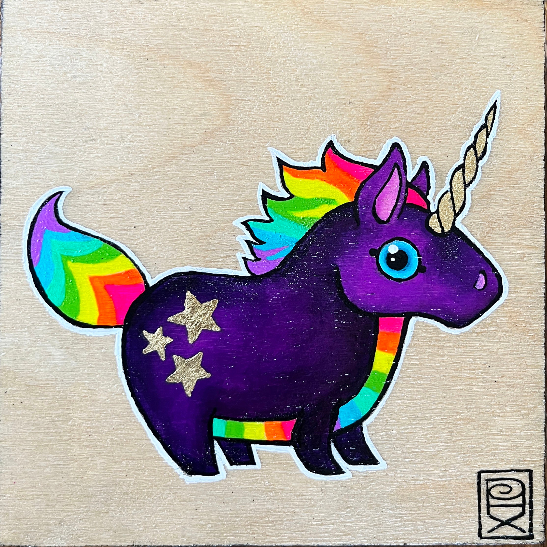 Colorful unicorn sticker with rainbow tail and horn on a wooden background