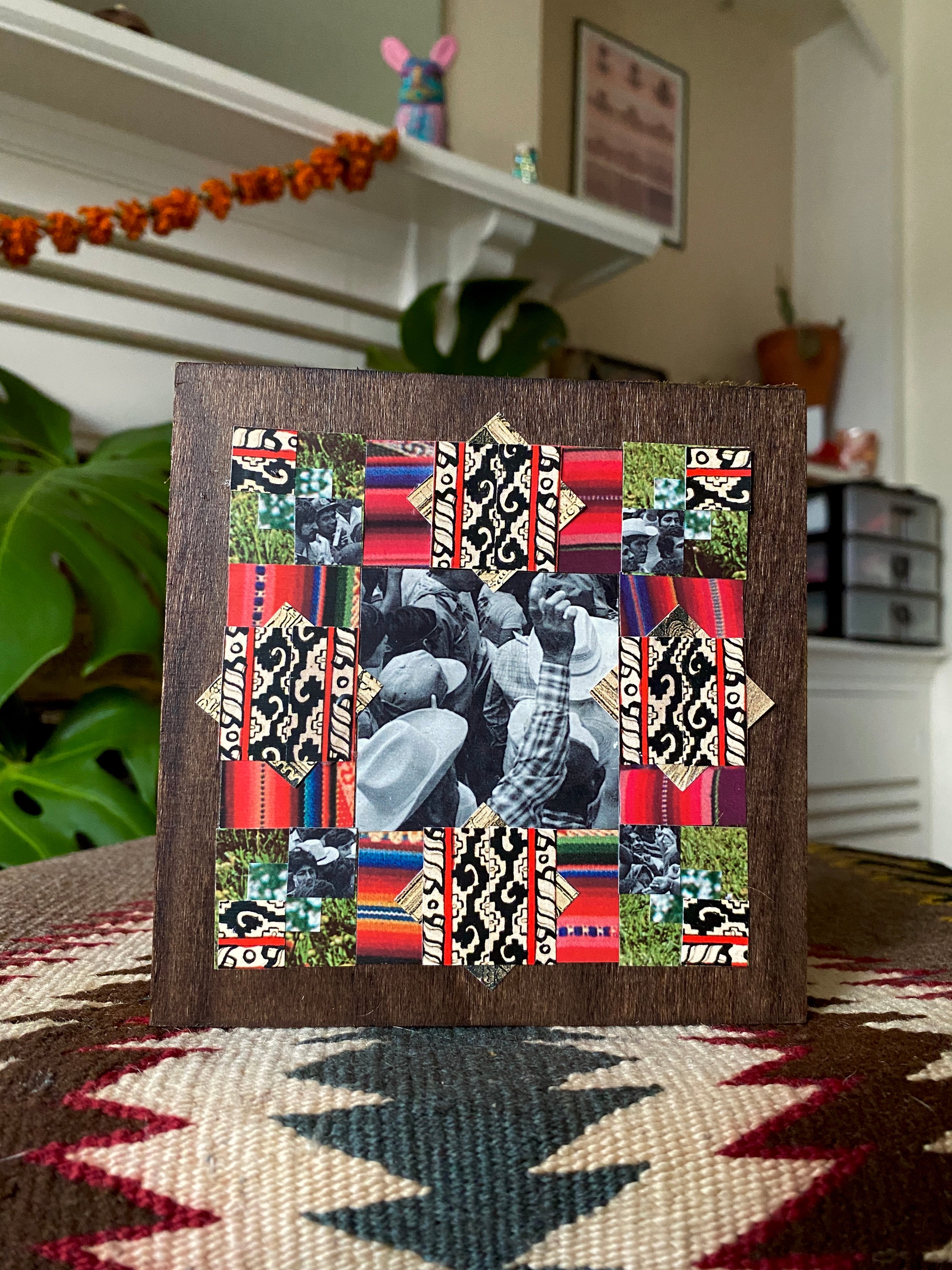 Decorative collage with patterns and images in a wooden frame on a rug.